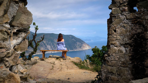 Woman standing on rock against sky