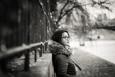 Side view of young woman standing by retaining wall during winter