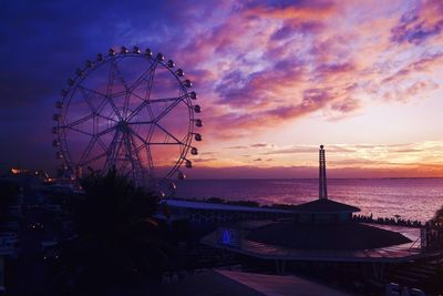 Ferris wheel at beach against sky during sunset