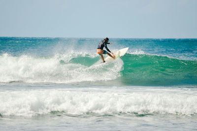 Man surfing in sea against sky