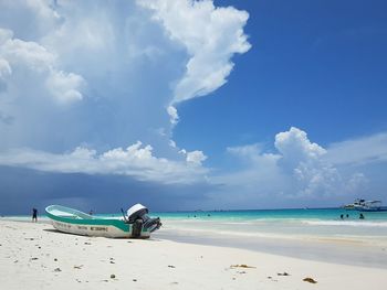 Boat at beach against cloudy sky