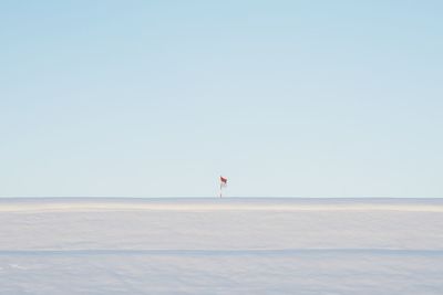 Flag on snow covered field against clear sky