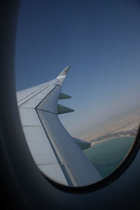 Airplane wing against clear blue sky seen through window