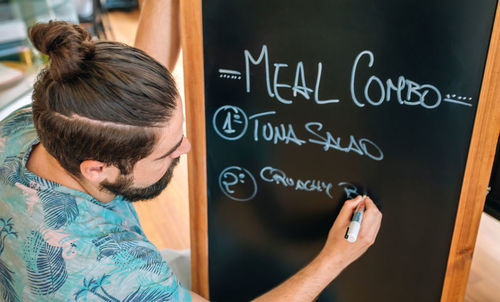 Man writing on blackboard in cafe