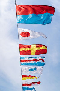 Nautical flags against blue sky in the wind at sunny day, vertical.