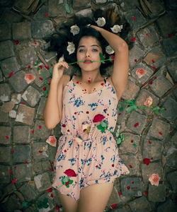 Portrait of beautiful young woman amidst flowers lying down on footpath