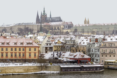Buildings by river in city during winter