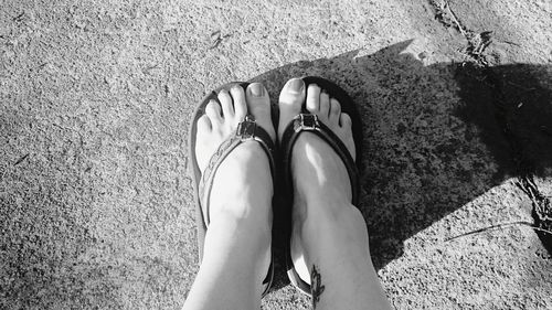 Low section of woman wearing flip-flops on footpath