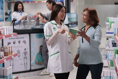Side view of female friends standing in laboratory