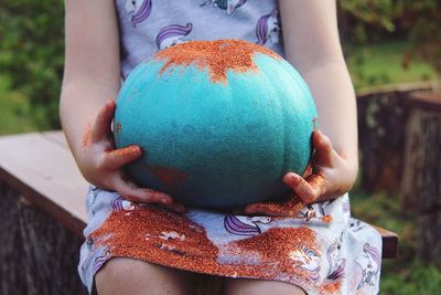 Close-up of girl holding painted pumpkin