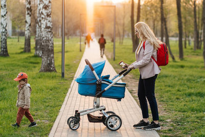 Mom walks with stroller and toddler son in the park