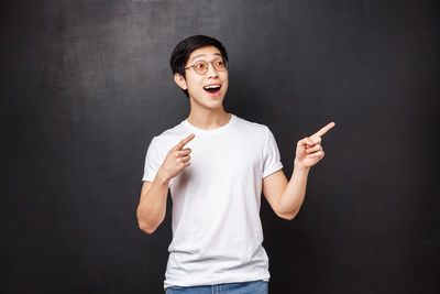 Portrait of young man gesturing against black background