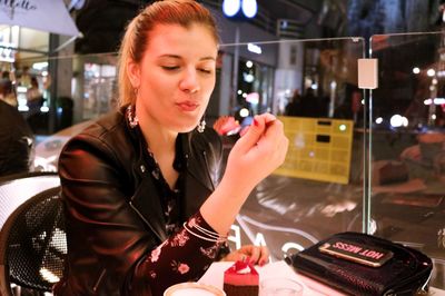 Young woman having cake in restaurant at night