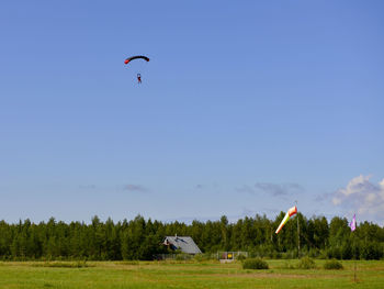 People flying over field against sky