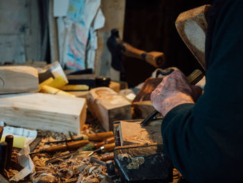 Midsection of man carving wood in workshop