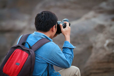 Backpack man photographing rock formation 