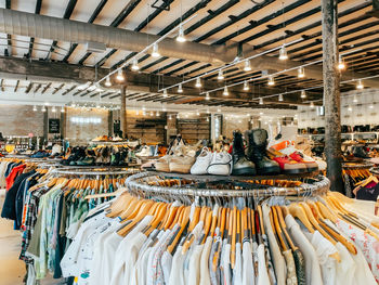 Brightly lit thrift shop showcases an array of second hand clothing on organized racks. 