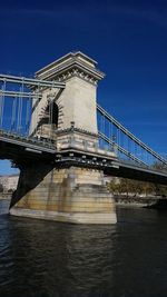 Low angle view of suspension bridge against blue sky