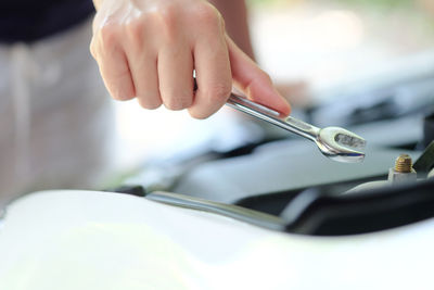 Close-up of hand repairing car engine