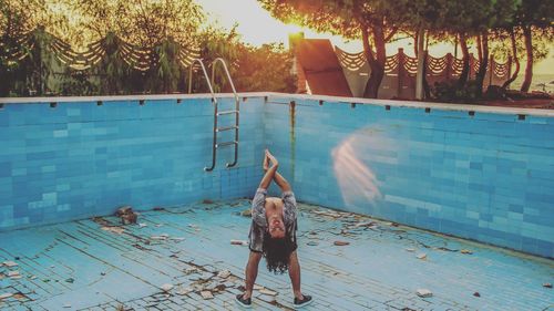 Girl standing by swimming pool against trees