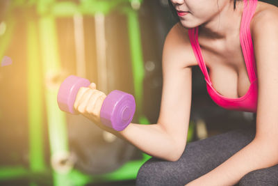 Midsection of woman holding dumbbell