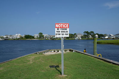 Information sign by sea against sky