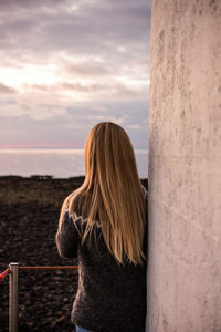 Rear view of woman standing by railing against sky