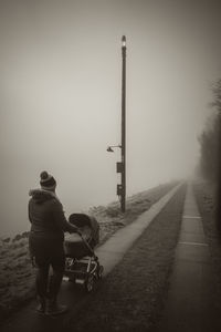 Rear view of men walking on road against sky