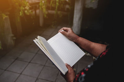 Midsection of man holding diary