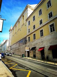 Road by buildings against sky in city