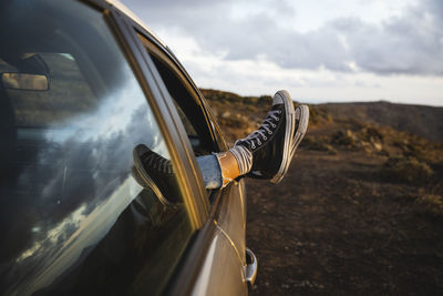 Woman with feet up on car window at sunset