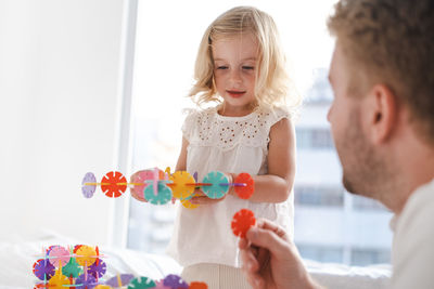 Side view of father and daughter playing with construction 