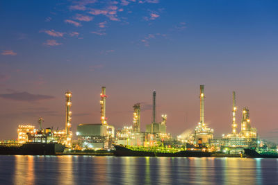 Illuminated factory against sky at night