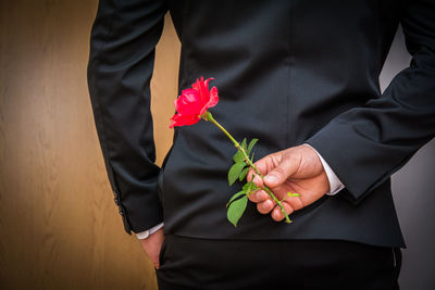 Midsection of man holding red roses