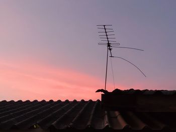 Low angle view of silhouette house roof against sky during sunset