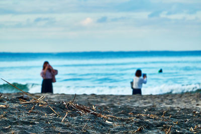 Rear view of man standing on beach against sky