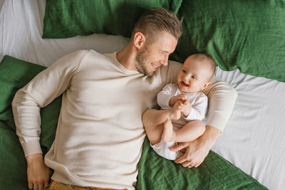 A happy father is lying on the bed with his little child. conception of family