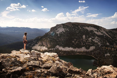 Rear view of man standing on rock against sky