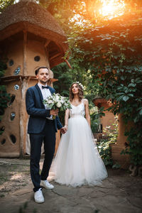 Smiling couple holding bouquet while standing in forest