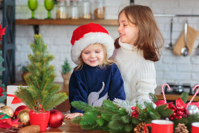 Portrait of smiling friends standing by christmas tree