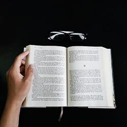 Cropped image of hand holding book over white background