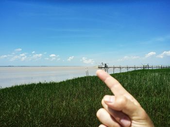 Optical illusion of person touching pier against blue sky