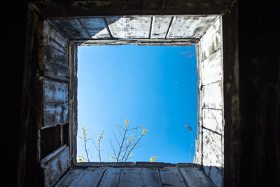 Directly below shot of clear blue sky seen through abandoned building