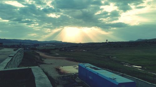 Road passing through landscape against cloudy sky