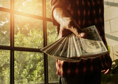 Midsection of man holding paper currency