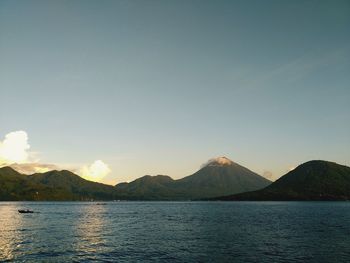 Scenic view of sea by mountains against sky