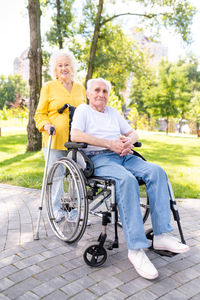 Portrait of woman using mobile phone while sitting on wheelchair in park