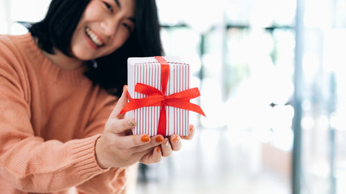 Portrait of smiling young woman holding gift box