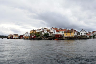 Houses by sea against sky in town