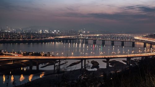 Calm river with illuminated buildings in background